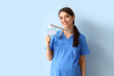 Mavi arka planda rozeti olan kadın stajyer doktor.