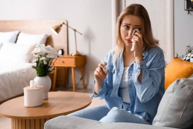 Evde göz damlası olan alerjisi olan genç bir kadın.