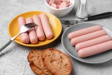 Gri arka planda lezzetli ince sosisli tabak ve tabaklar.