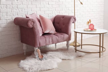 Sıcak pembe koltuk, kahve masası ve kürk halısı beyaz tuğla duvar.