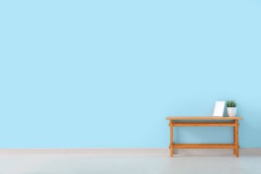 Ev bitkisi ve mavi duvarın yanındaki boş çerçeveli ahşap masa.