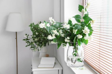 Pencere kenarında yasemin çiçekleri olan vazo, yakın plan.