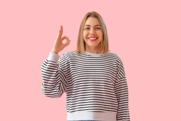 若いです女性でストライプスウェットシャツショーOk上のピンクの背景 — ストック写真