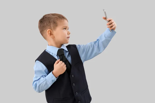 Симпатичний Маленький Бізнесмен Мобільним Телефоном Бере Селфі Сірому Фоні — стокове фото