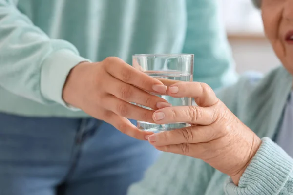 Young Woman Giving Glass Water Her Grandmother Home Closeup — Stock Photo, Image
