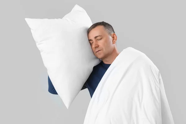 成熟した男とともに柔らかい枕と毛布上灰色の背景 — ストック写真