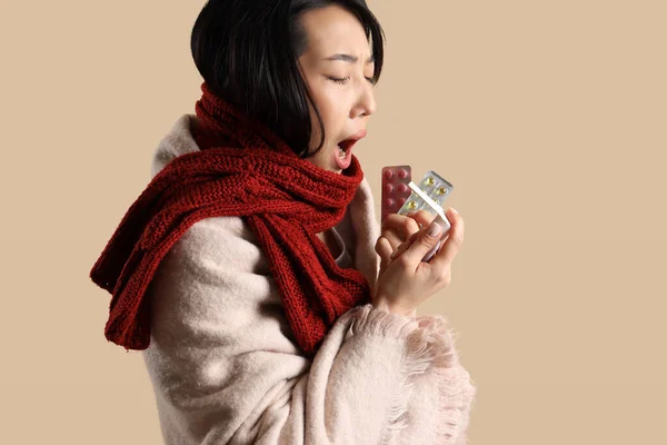 病気アジアの女性とともに丸薬とスプレーのための喉上ベージュの背景 — ストック写真