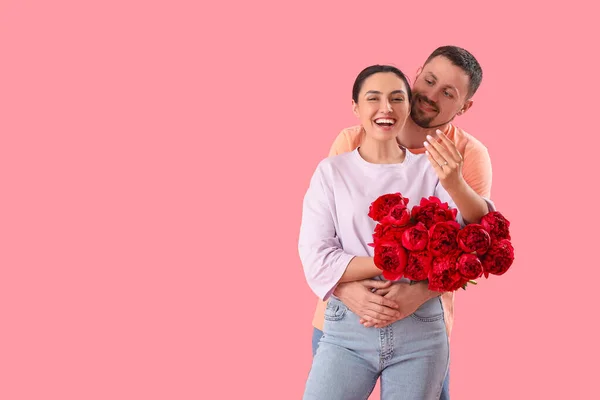 Šťastný Zasnoubený Pár Květinami Objímání Růžovém Pozadí — Stock fotografie