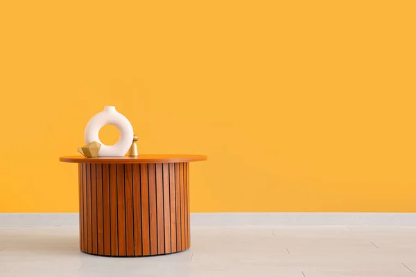 Holztisch Mit Leerer Vase Und Dekorativen Figuren Der Orangefarbenen Wand — Stockfoto