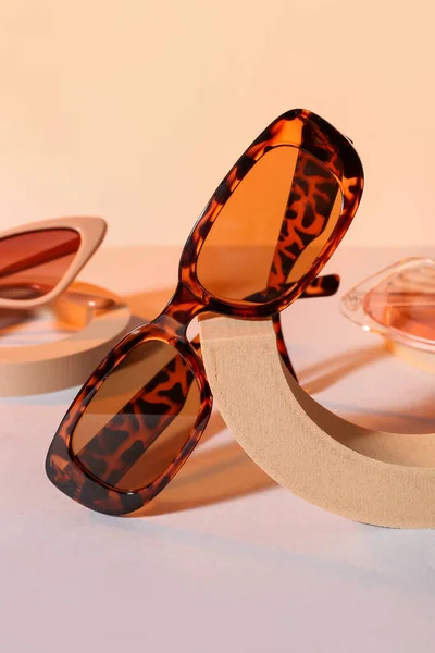 Podien Mit Verschiedenen Stylischen Sonnenbrillen Auf Beigem Hintergrund — Stockfoto