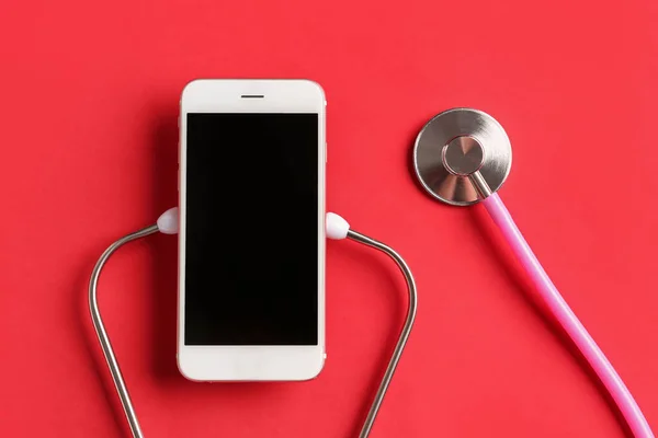 stock image Stethoscope and mobile phone on red background