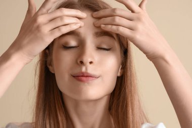 Bej arka plan üzerinde yüz geliştirme egzersizi yapan genç kadın, yakın plan.