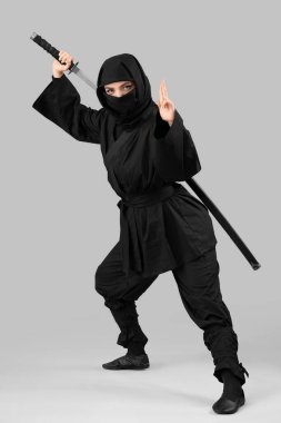 Gri arka planda kılıcı olan bir kadın ninja.