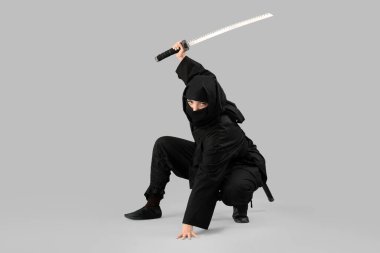 Gri arka planda kılıcı olan bir kadın ninja.
