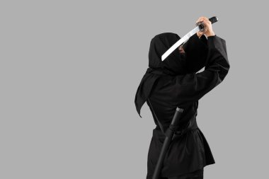 Gri arka planda kılıcı olan bir kadın ninja.