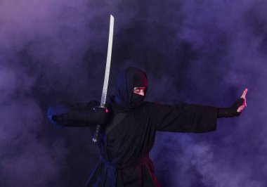 Siyah arka planda kılıç taşıyan erkek ninja.