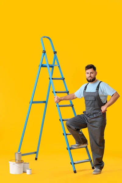 Male Worker Ladder Cans Paint Yellow Background — Stok fotoğraf
