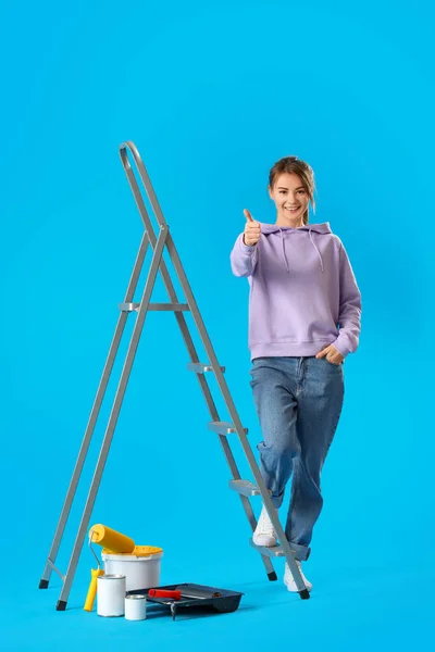 Молодая Женщина Лестницей Банками Краской Показывает Большой Палец Вверх Синем — стоковое фото