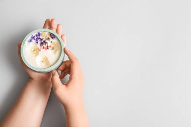 Yanan mumu ve gri arka planda çiçekleri olan kadın elleri