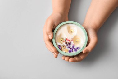 Yanan mumu ve gri arka planda çiçekleri olan kadın elleri