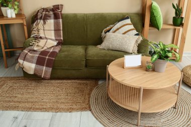 Oturma odasında rahat yeşil kanepe, ahşap sehpa ve raf ünitesi var.