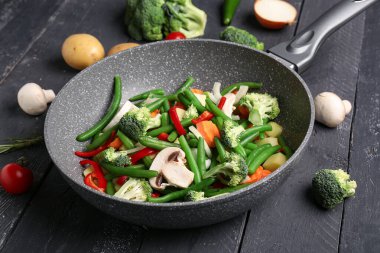 Siyah ahşap arka planda taze sebzeli tava.