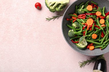 Pembe arka planda taze sebzeli tava.