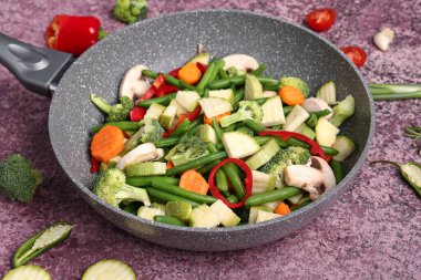 Mor arka planda taze sebzeli kızartma tavası