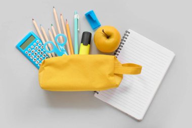 Taze elma, hesap makinesi ve gri arkaplanda farklı kırtasiye malzemesi olan defter.