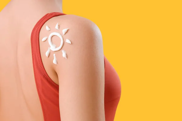 若いです女性とともに太陽製の日焼け止めクリーム上の彼女の肩の上に黄色の背景 クローズアップ — ストック写真