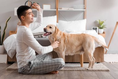 Yatak odasında Labrador köpeği olan genç bir adam.