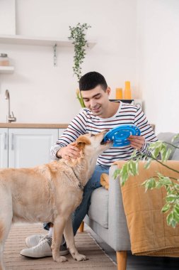 Genç adam mutfakta şirin Labrador köpeğiyle oynuyor.