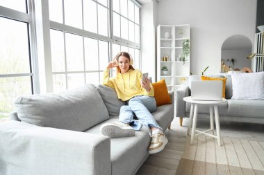 Evde cep telefonu kullanan kulaklıklı bir kız öğrenci.