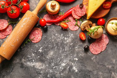 Koyu arkaplanda pizza hazırlamak için farklı malzemeler.