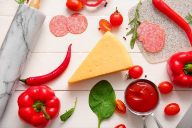 Açık ahşap arka planda pizza hazırlamak için farklı malzemeler.