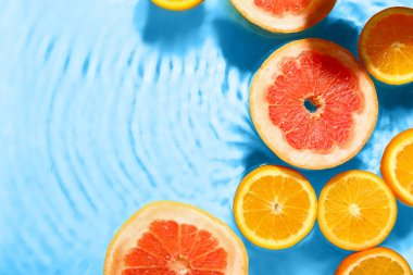 Turkuaz arka planda taze portakal ve suda greyfurt dilimleri.