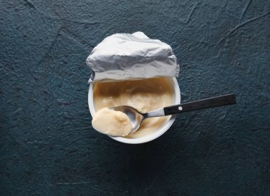 Siyah arka planda lezzetli krem peynirli plastik kap.