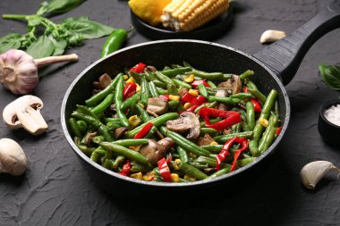 Siyah arka planda farklı sebzelerle kızartma tavası