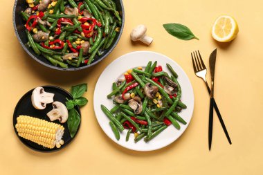 Kızartma tavası ve tabağı sarı arka planda farklı sebzelerle