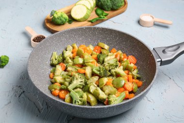Gri arka planda farklı sebzelerle kızartma tavası