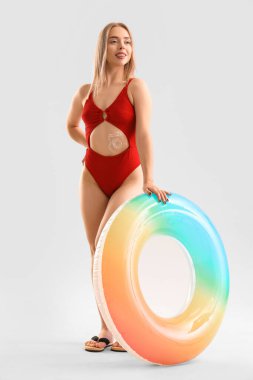 Uygulamalı güneş kremi ve hafif arka planda şişirilebilir yüzüğü olan genç bir kadın.