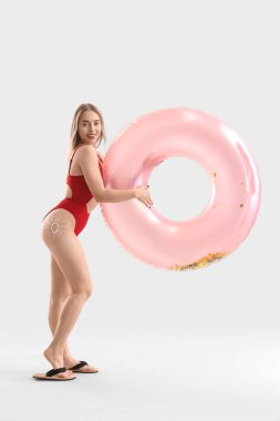 Güneş kreminden yapılmış genç bir kadın ve arka planda şişme bir yüzük.