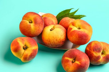 Tatlı şeftalili kağıt tabak ve mavi arka planda yapraklar.