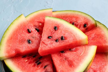 Mavi zemin üzerinde taze karpuz parçaları olan bir tabak.
