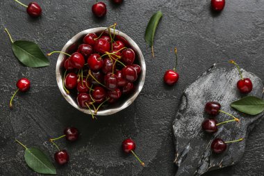 Siyah arka planda vişneli kase ve yemek.