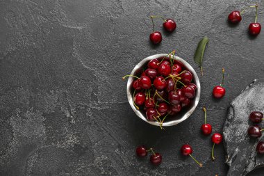 Siyah arka planda vişneli kase ve yemek.