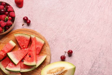 Taze karpuz parçaları ve pembe arka planda bir kase farklı böğürtlen.