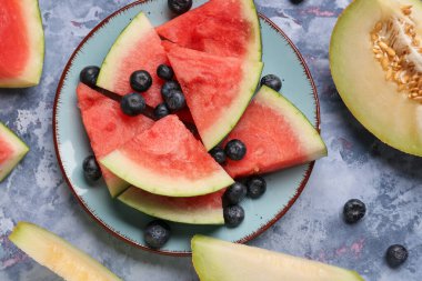 Taze karpuz parçaları ve mavi arka planda farklı böğürtlenler.