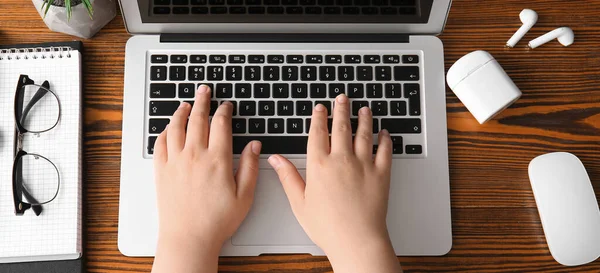 女性程序员在木制桌旁使用笔记本电脑的手 顶部视图 — 图库照片