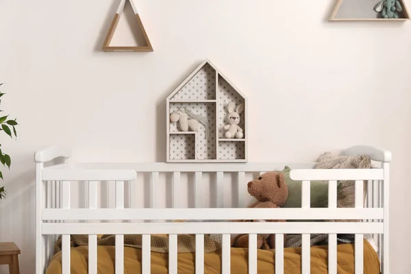 stock image Baby crib with toy bear in light bedroom